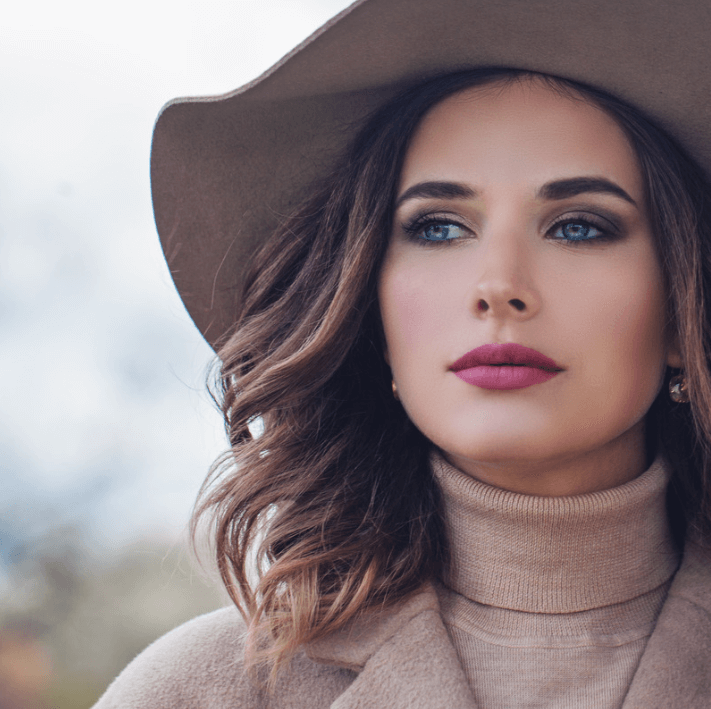 Lippenpflege-Essenzöl, elegant gestylte Frau mit Hut und gepflegten Lippen, die strahlen.